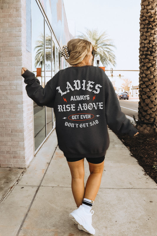 a woman walking down a sidewalk wearing a black sweatshirt