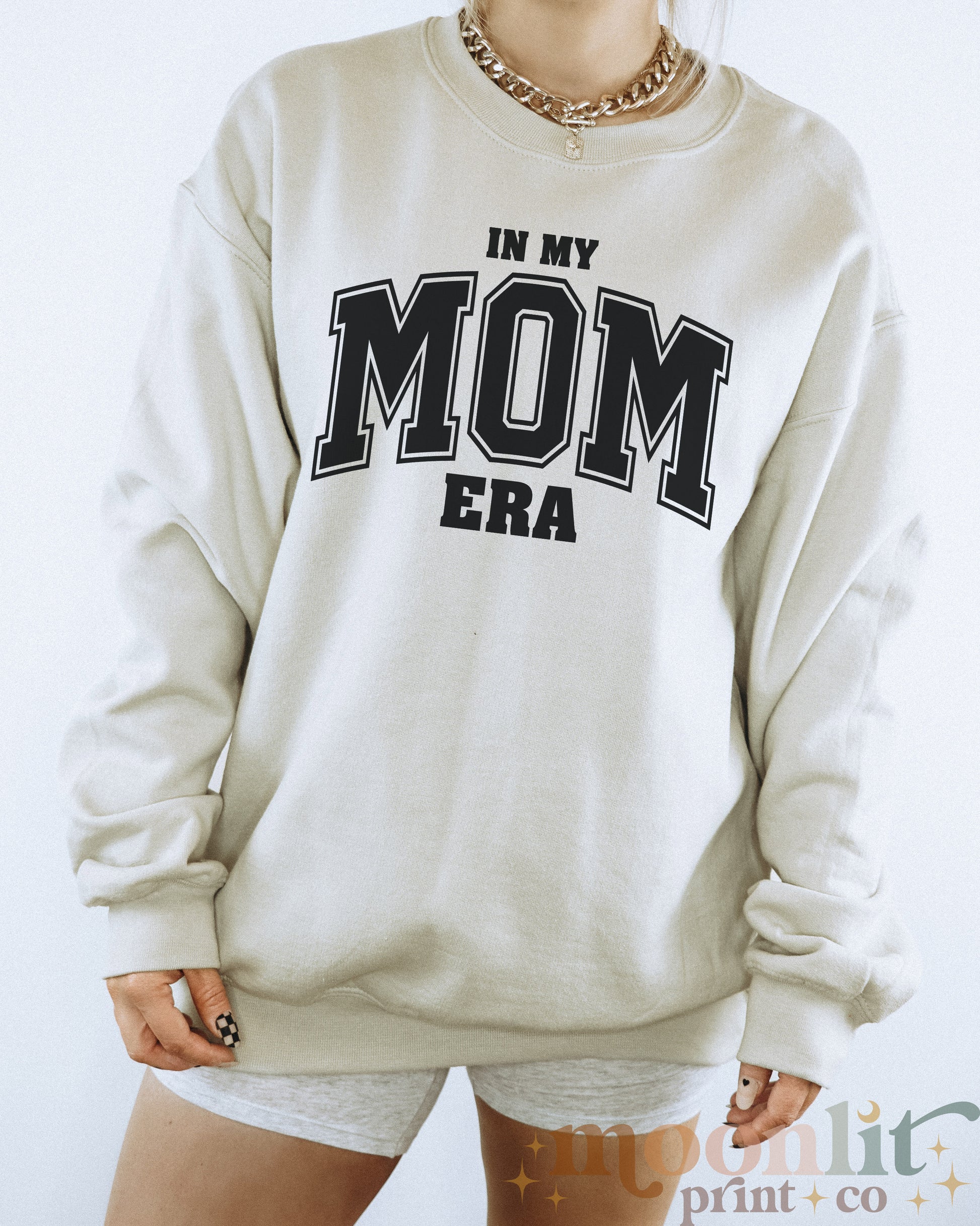 a woman wearing a sweatshirt that says in my mom era