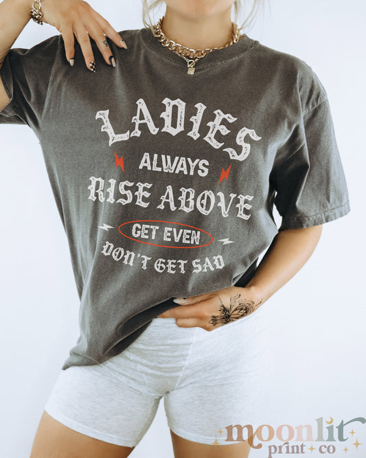 a woman wearing a shirt that says ladies always rise above get even don't