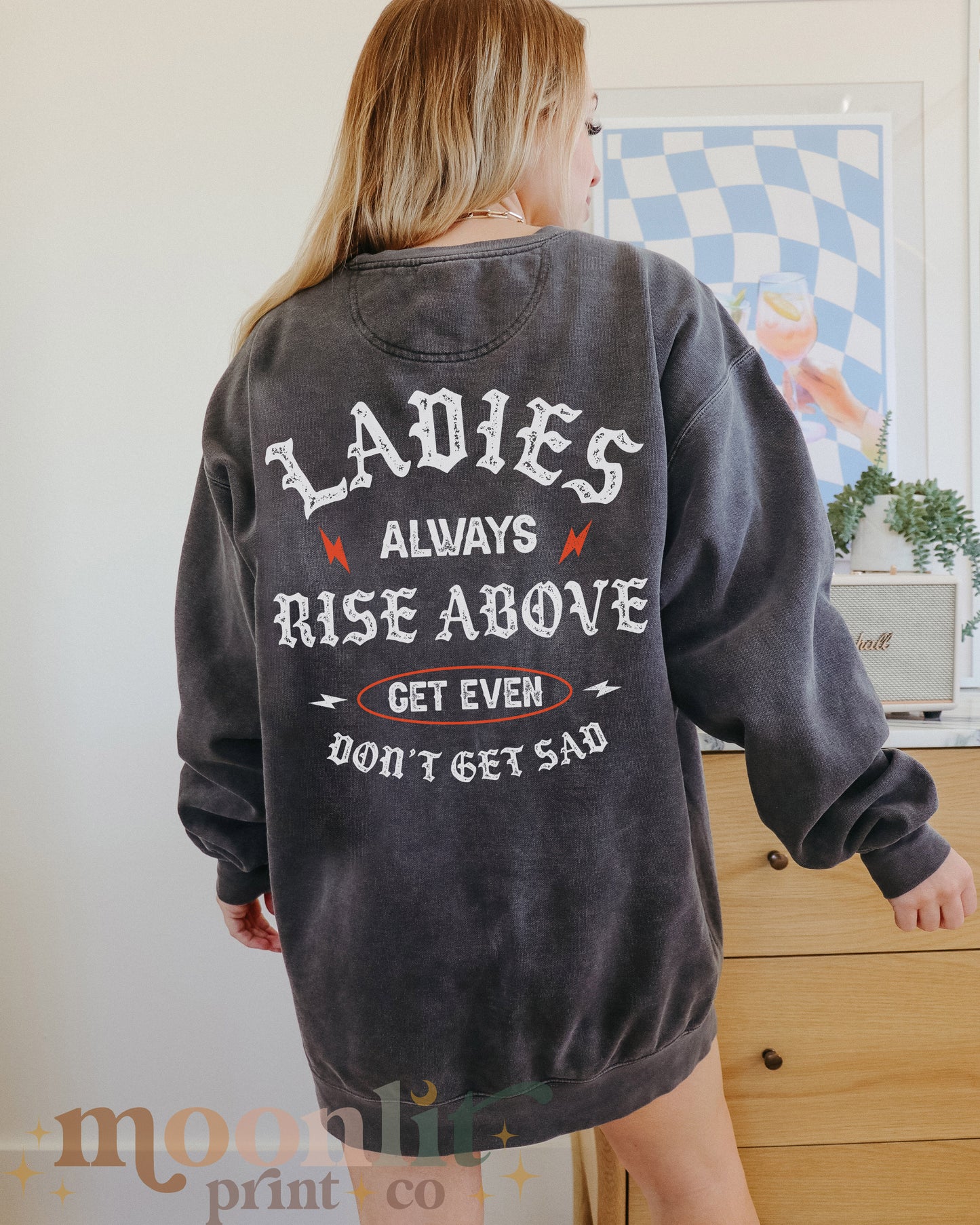 a woman wearing a sweatshirt that says ladies always rise above get even don't