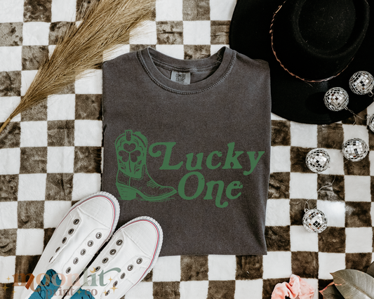 a t - shirt that says lucky one next to a pair of sneakers