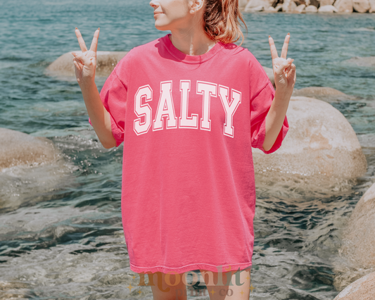 a girl in a pink shirt is standing by the water